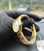 Close-up of the crown on the Cartier Baignoire Small Model sapphire yellow gold women's watch.