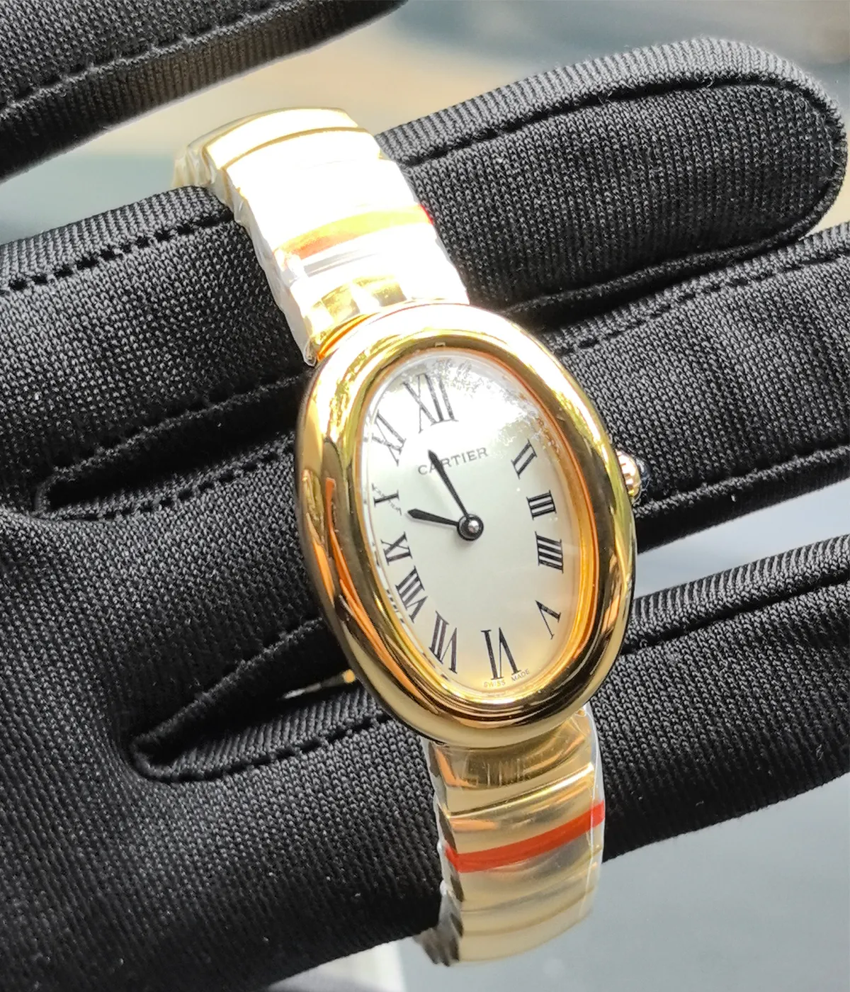 Cartier Baignoire Small Model sapphire yellow gold women's watch being worn on the wrist.