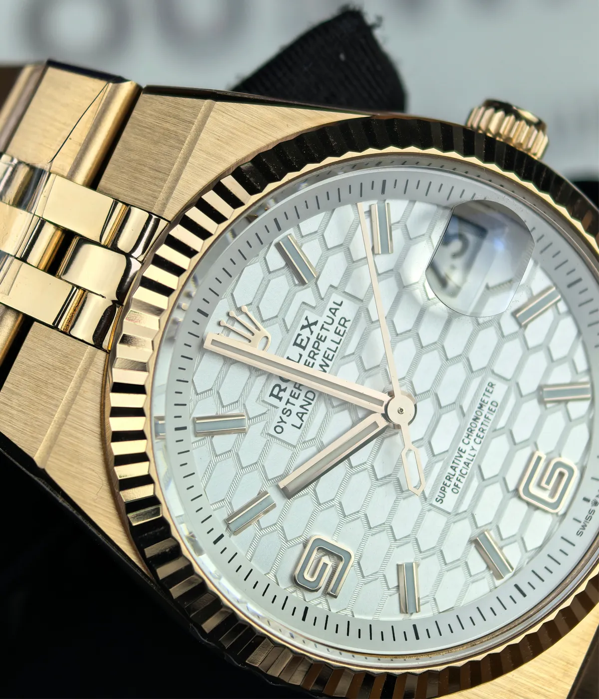 Close-up of the dial and bezel details on the Rolex Land-Dweller 127335-0001 with a rose gold case and white honeycomb textured dial.
