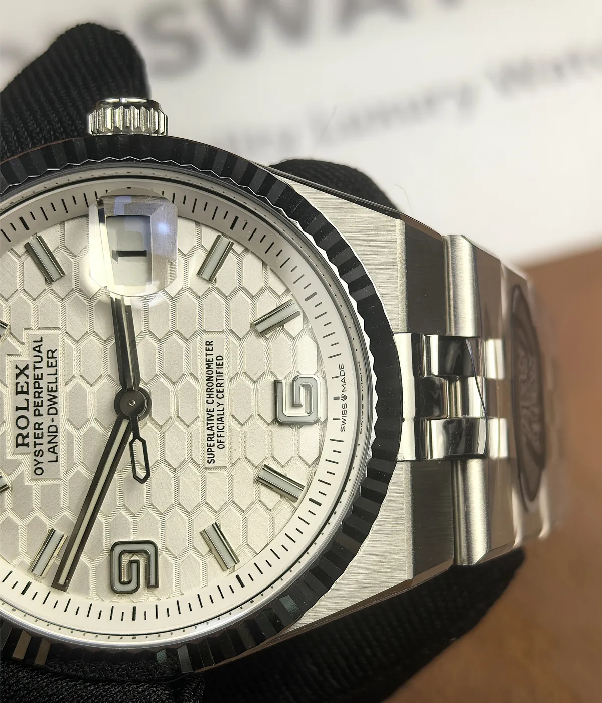 Close-up of the bezel details on the Rolex Land-Dweller 127336-0001 with a platinum case and white honeycomb textured dial.