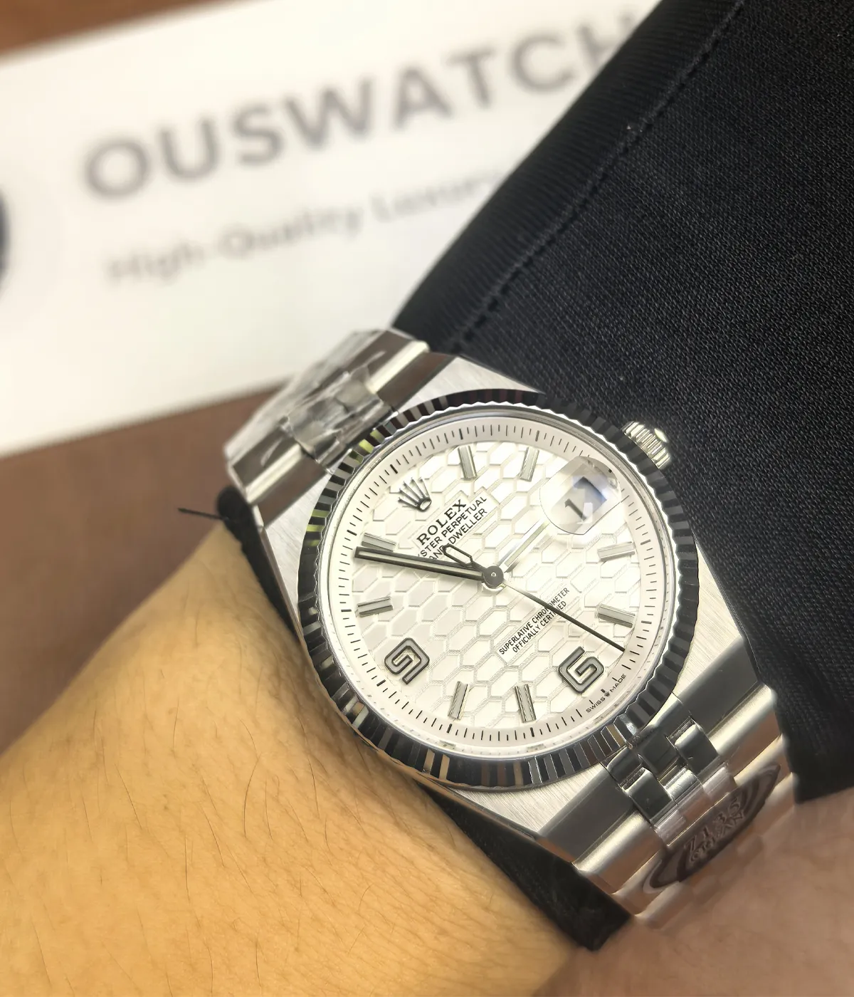 The Rolex Land-Dweller 127336-0001 with a platinum case, triangular grooved bezel, and white honeycomb textured dial being worn on the wrist.