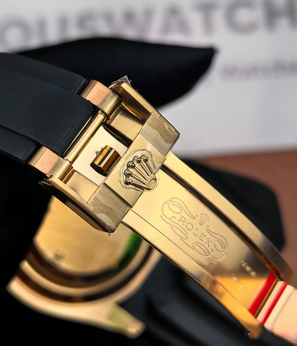 Close-up of the logo on the clasp of the Rolex Rose Gold Yachtmaster 126655-0002 with a black dial and rubber strap.