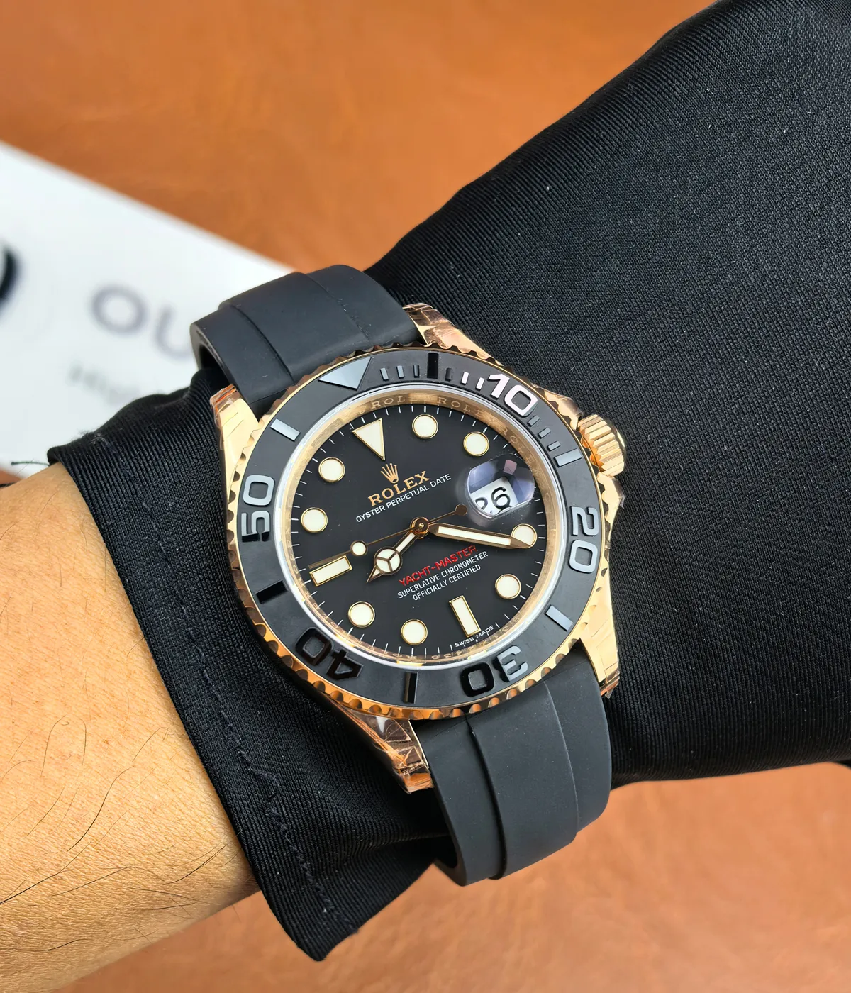 The Rolex Rose Gold Yachtmaster 126655-0002 with a black dial and rubber strap being worn on the wrist.